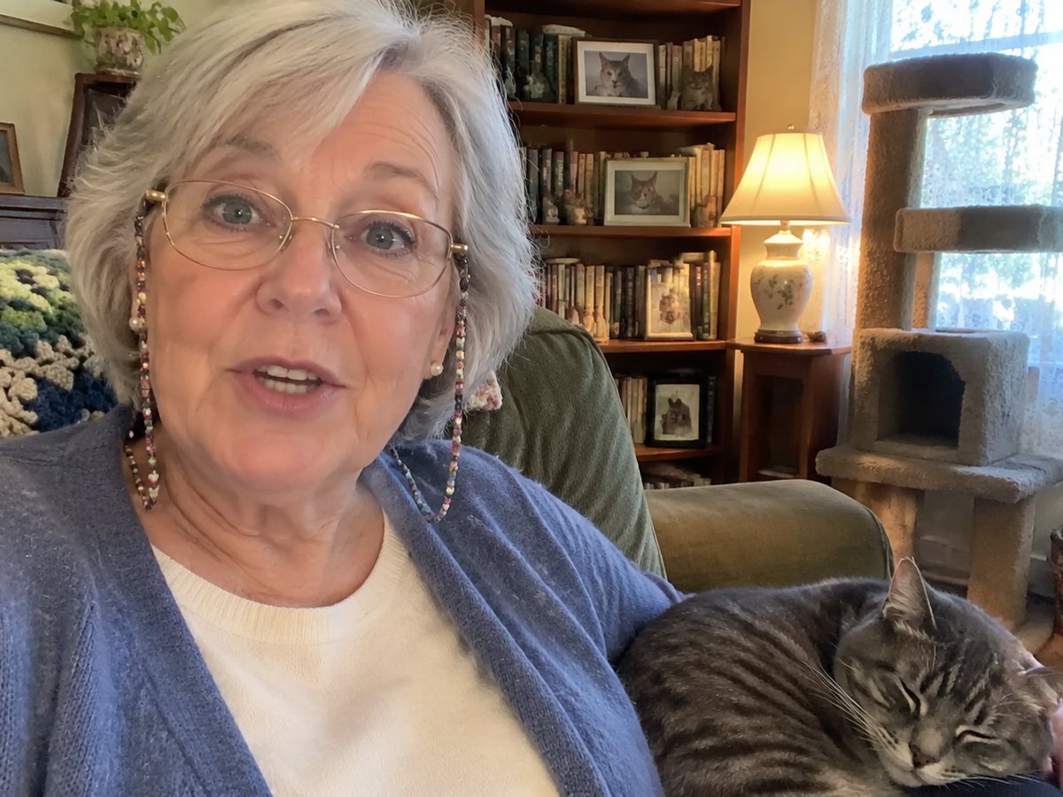 Margie in her armchair at home, with a grey tabby asleep beside her